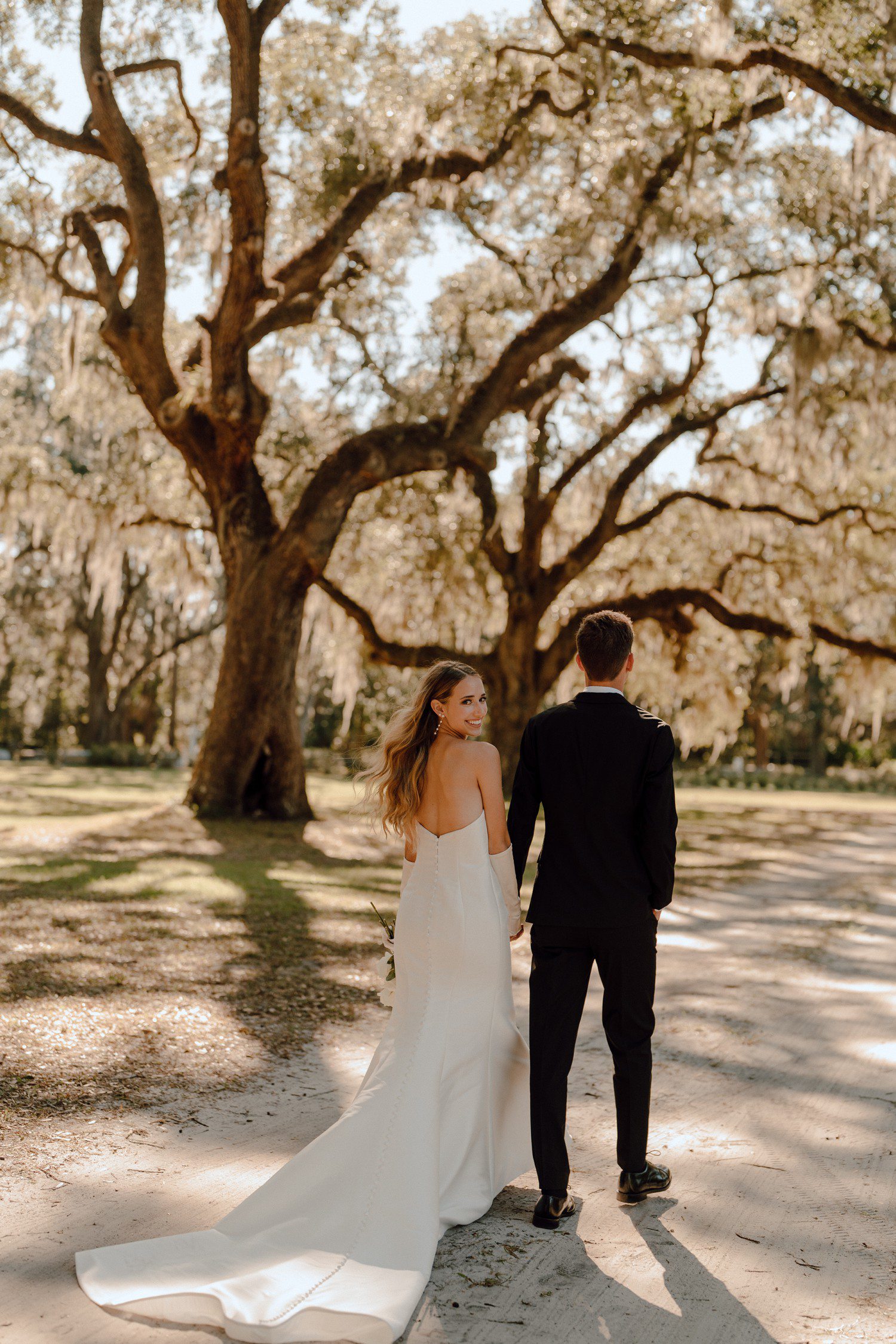 Bride and Groom Walking Under Spanish Moss Trees in South Carolina