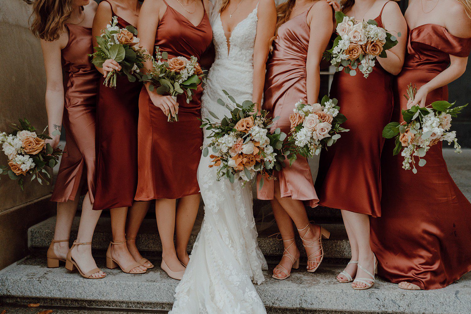 Bride with bridesmaids in burnt orange dresses with bouquets 