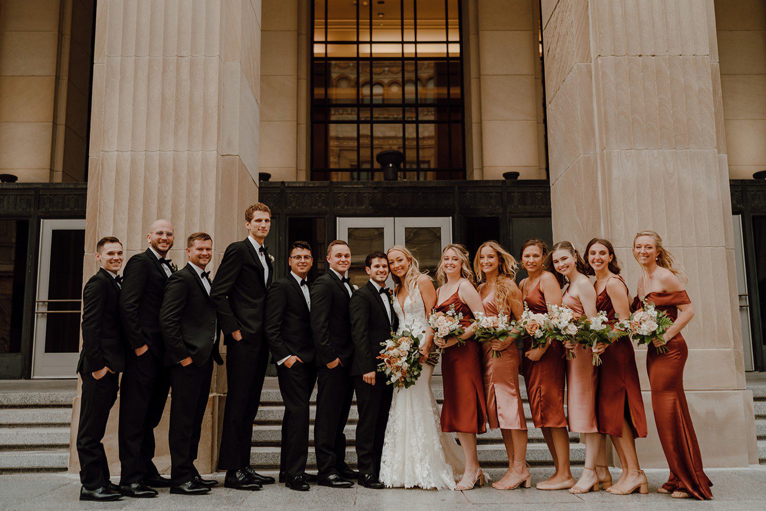 Wedding Party Photos with groosmen in black and bridesmaids in burnt orange 