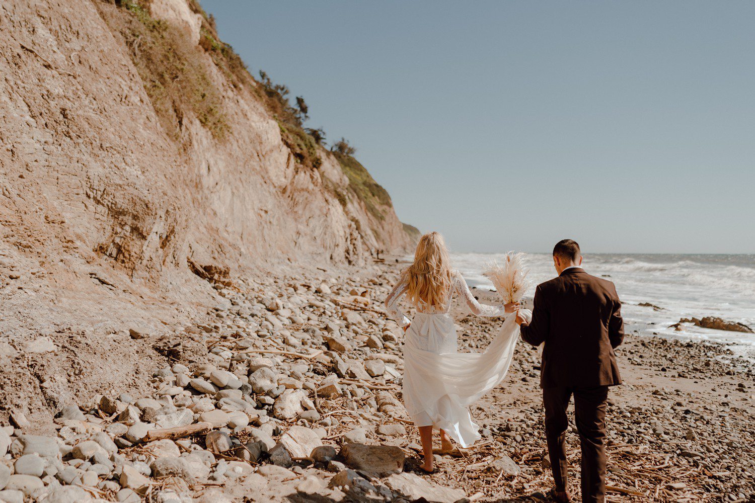 Bride and groom walking on beach in Santa Barbara, CA. 