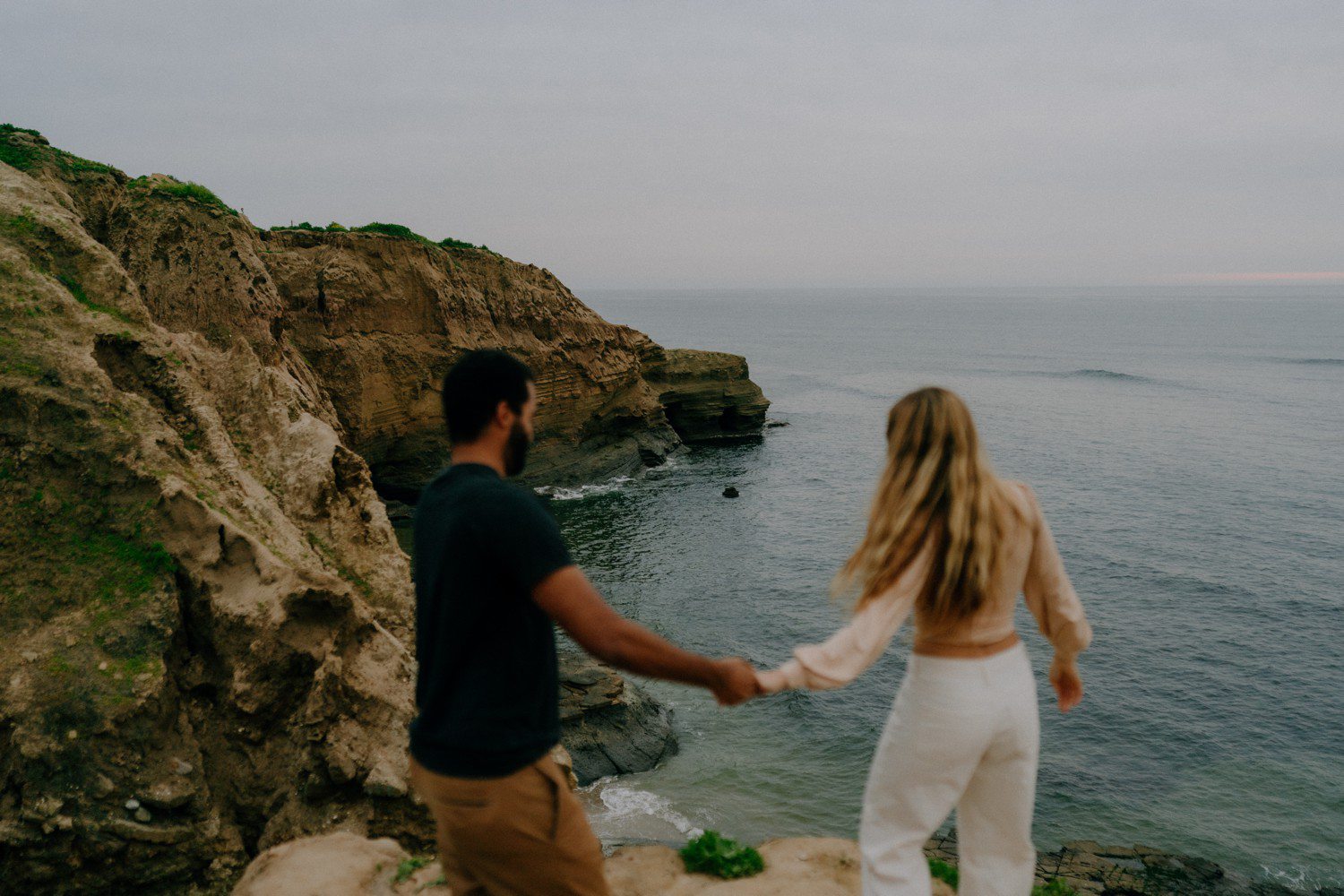 Couple holding hands and walking on Sunset Cliffs.