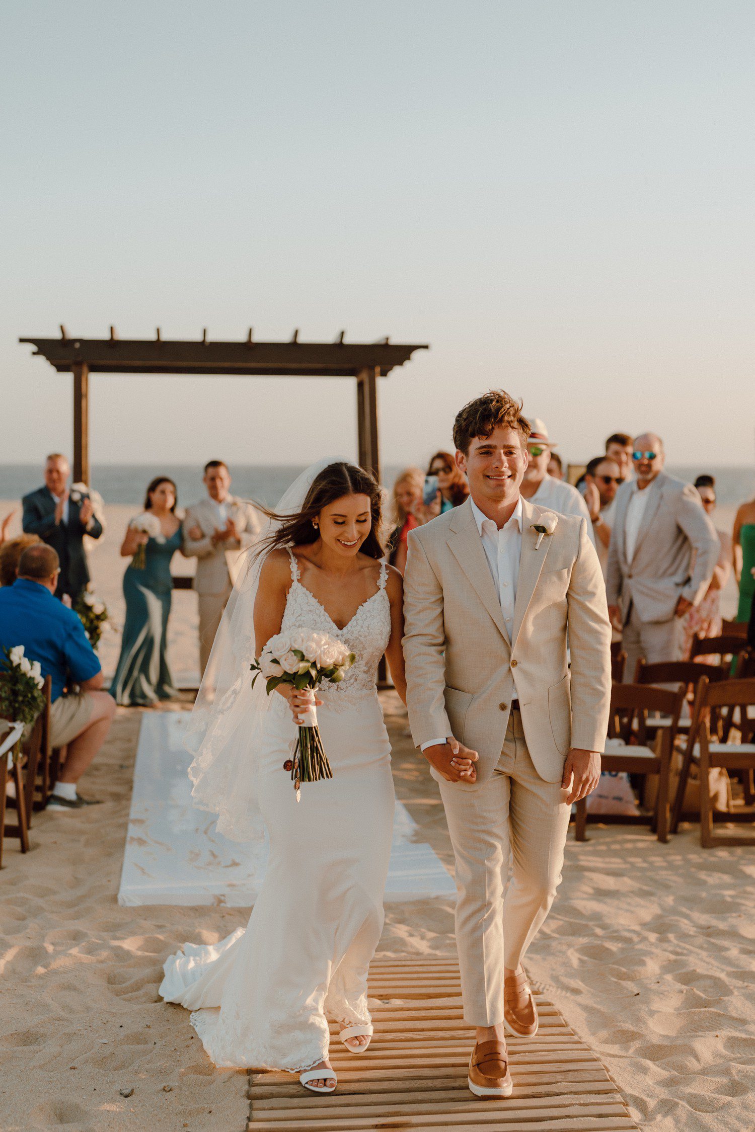 Bride and groom walking down aisle at beach wedding in Los Cabos. 