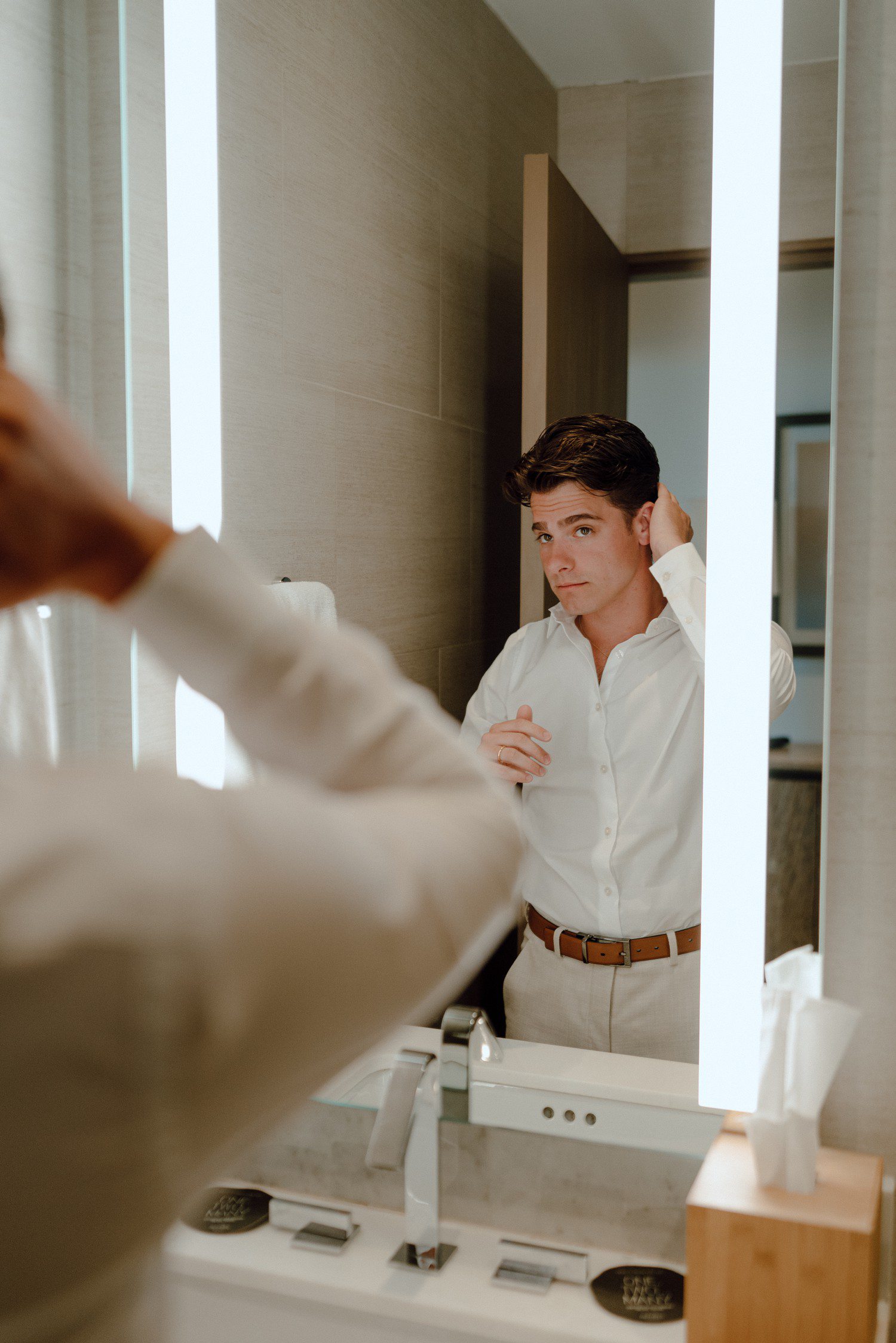 Groom getting ready in mirror at hotel. 