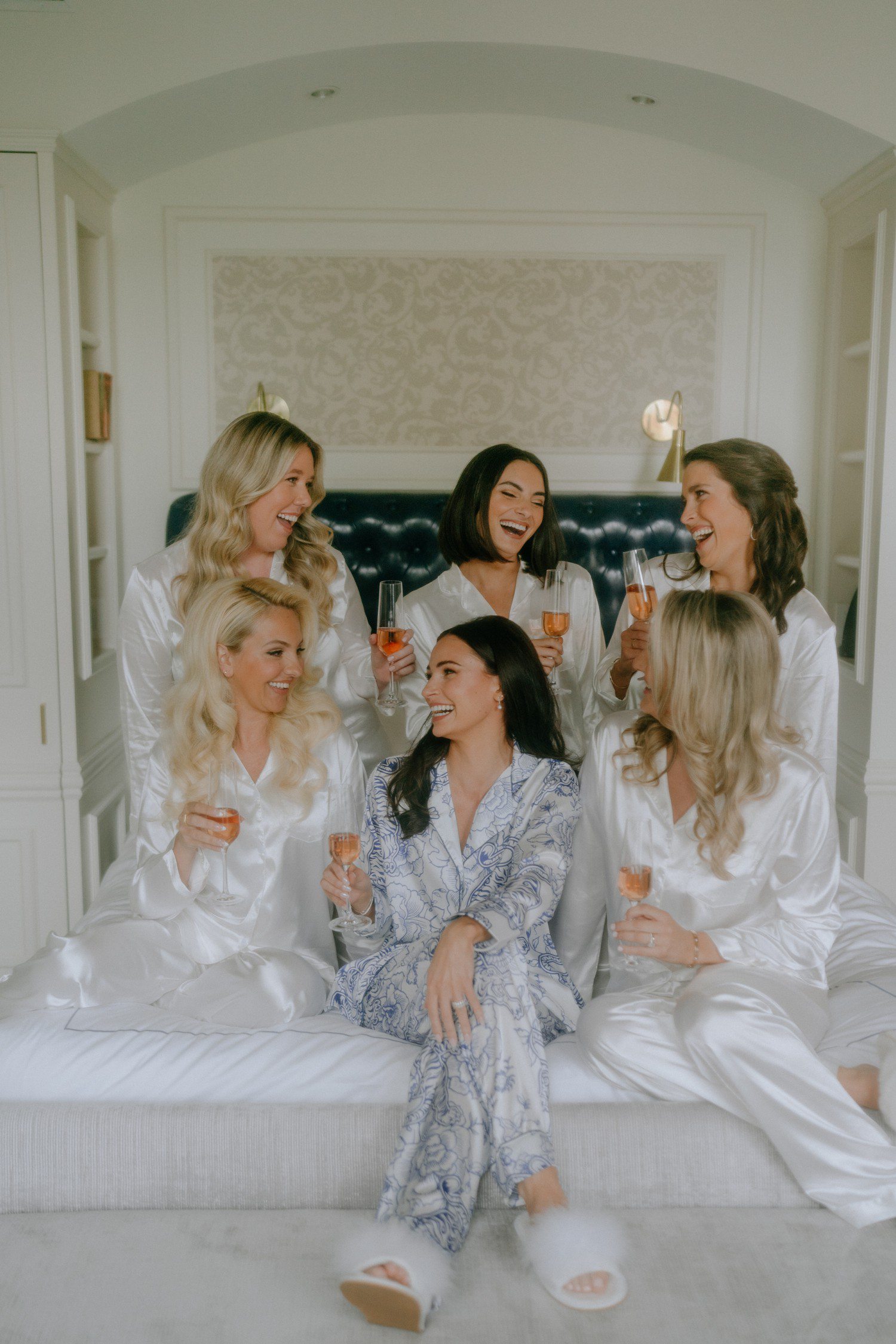 Bride and bridesmaids sitting on bed at Adelphi Hotel. 