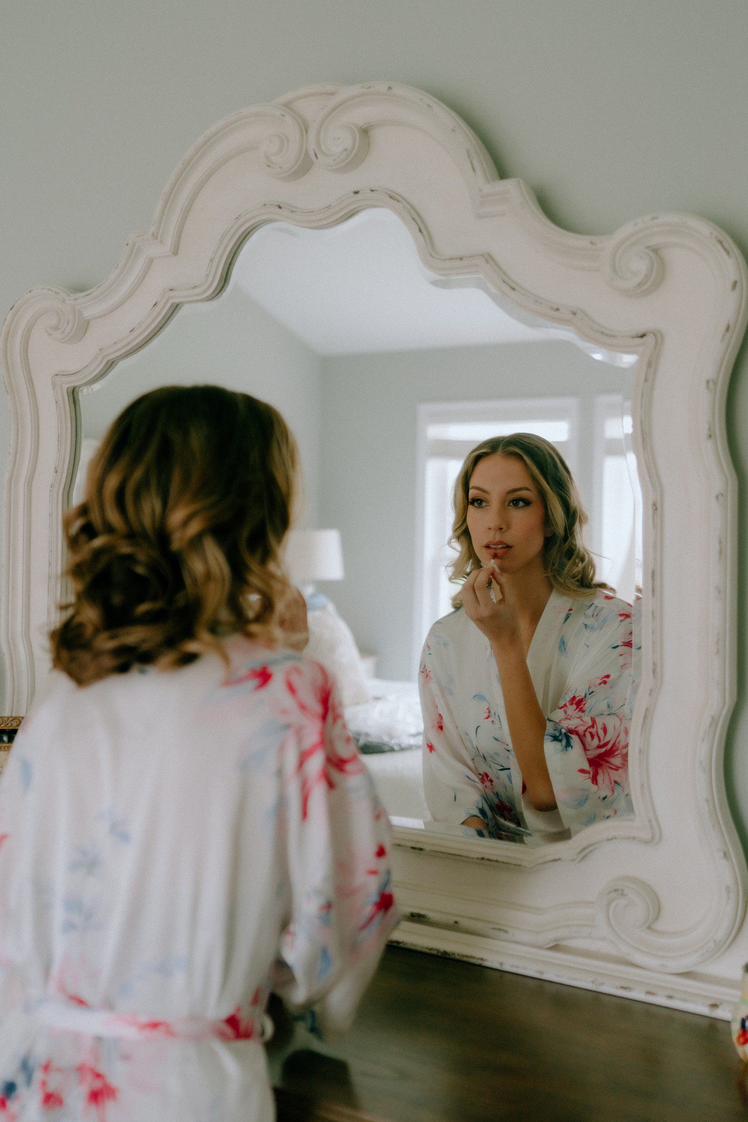 Bride putting on lipstick in mirror
