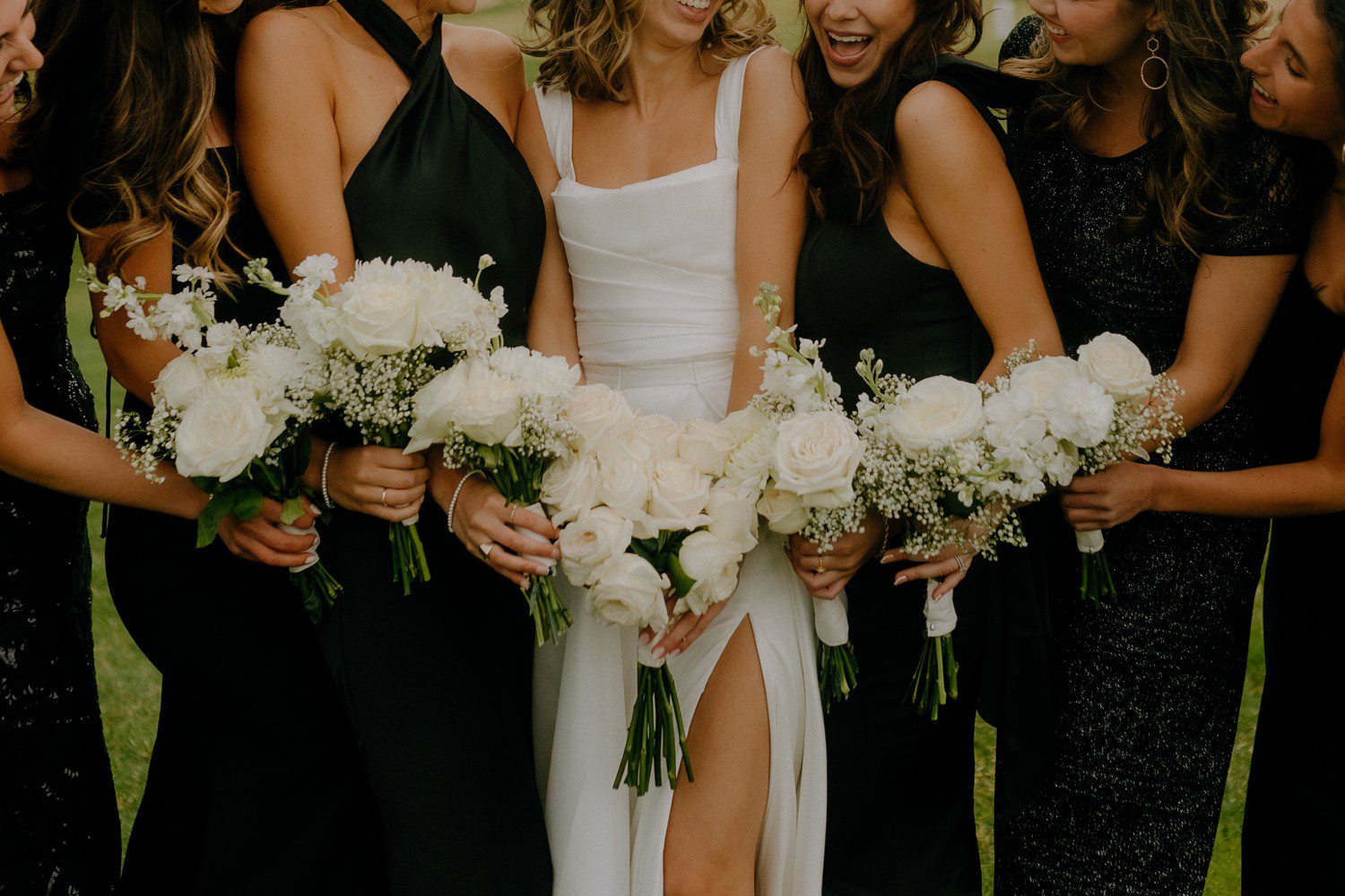 Black bridesmaid dresses with white bouquets. 