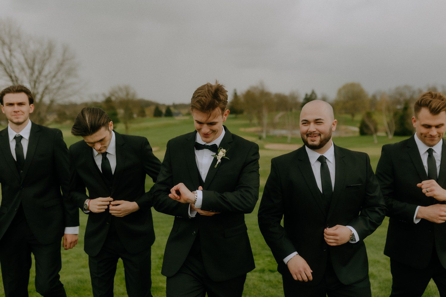 Groom walking with groomsmen in black suits. 