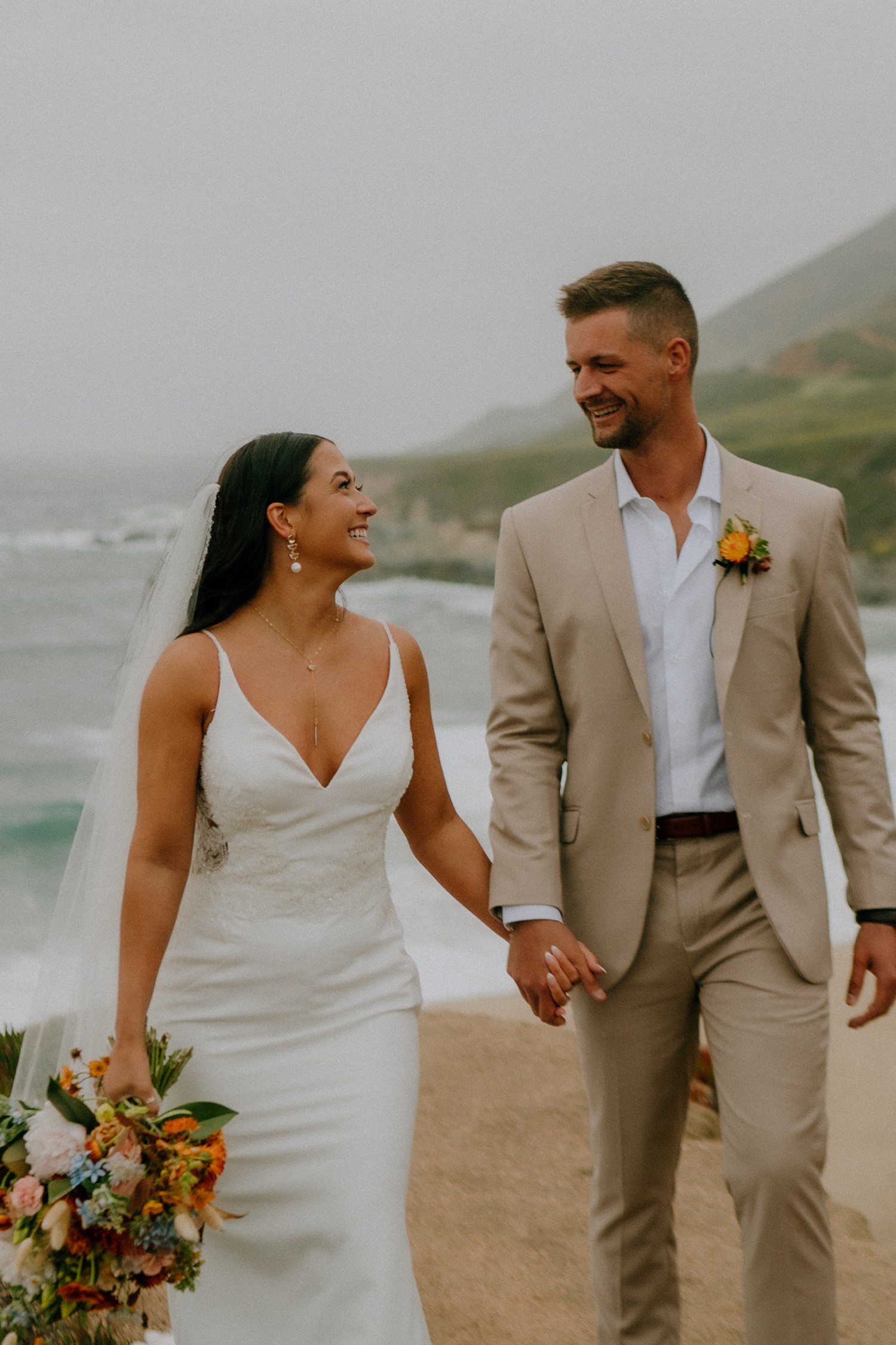 Couple walking together during elopement at Big Sur on the beach. 