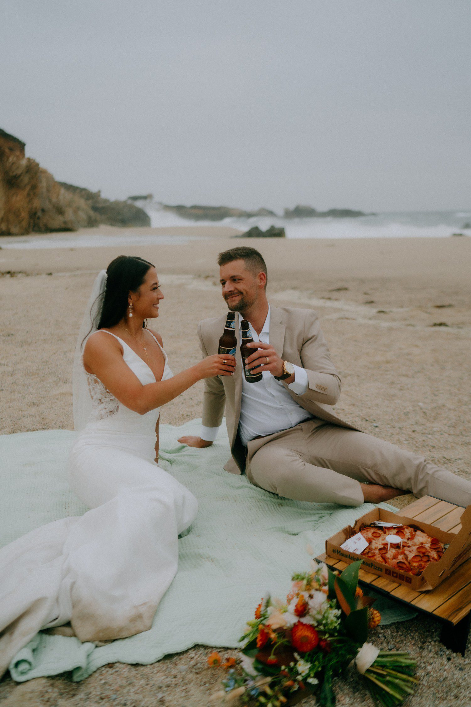 Elopement couple enjoying pizza and beer on the beach. 