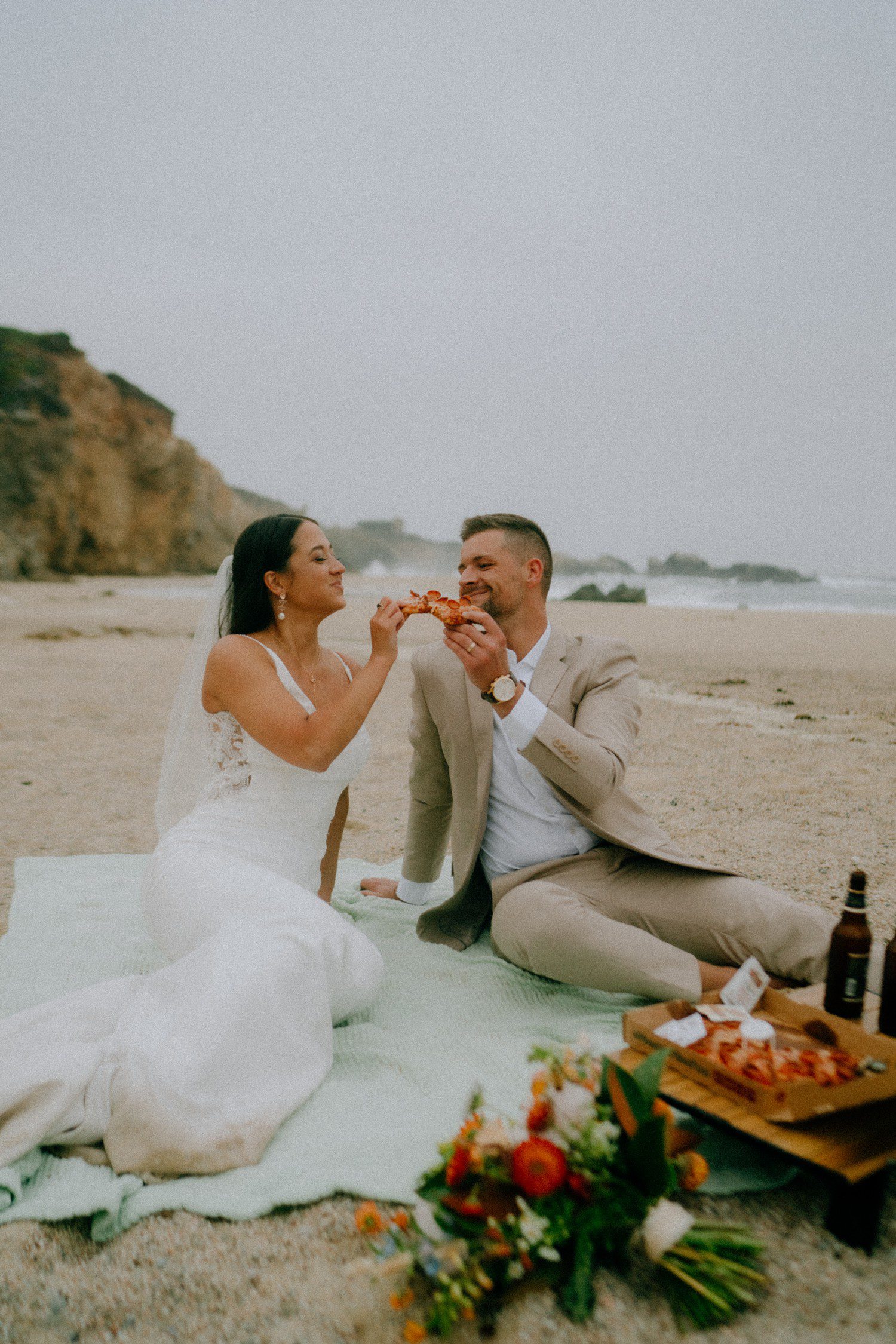 Big Sur beach elopement couple with pizza and beers. 