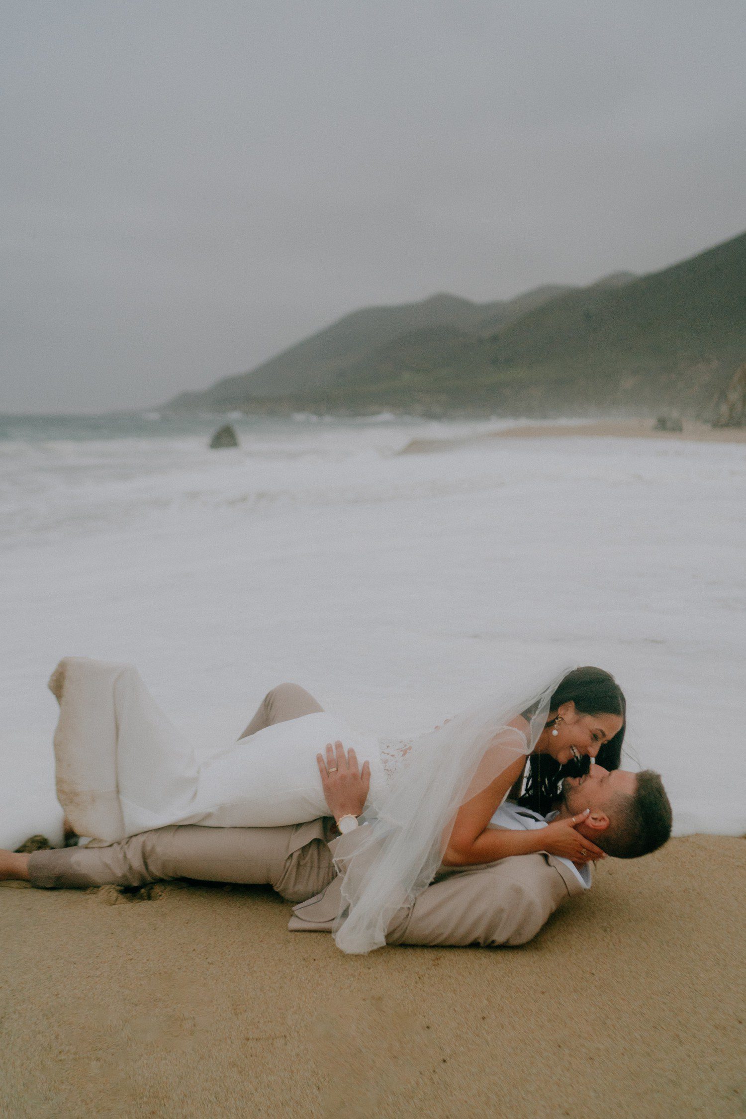 Wedding couple laying on Garrapata Beach for elopement photos. 