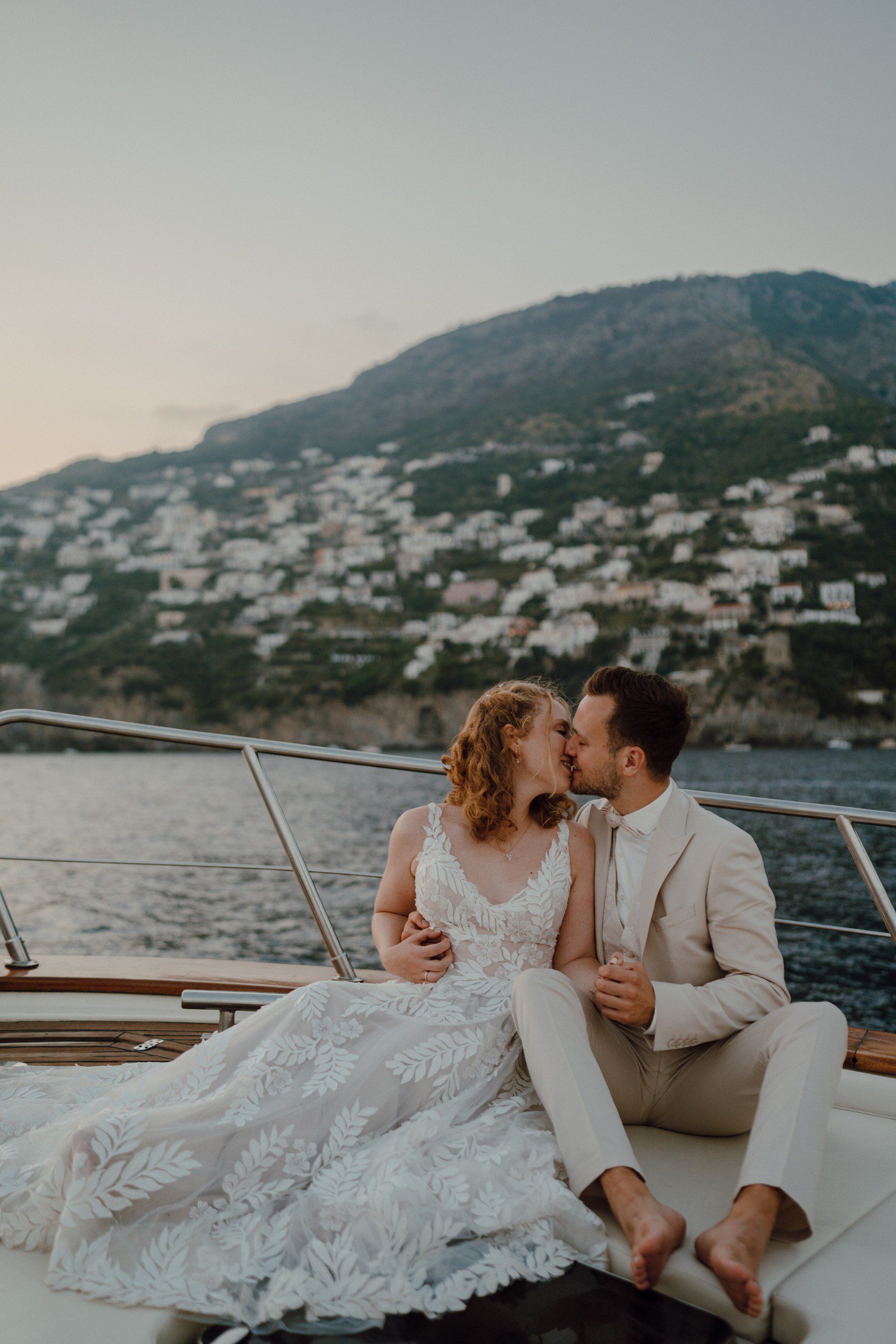 Bride and groom kissing on boat in Positano Italy. 