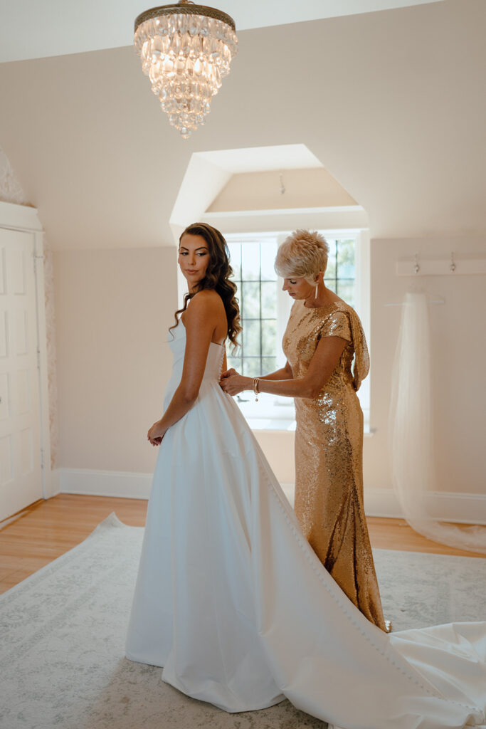 mother of the bride helping her get ready for the wedding ceremony