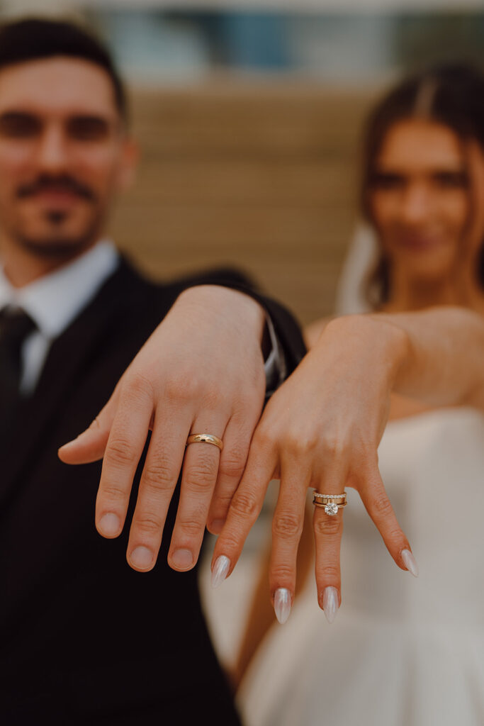 bride and groom showing their stunning wedding rings