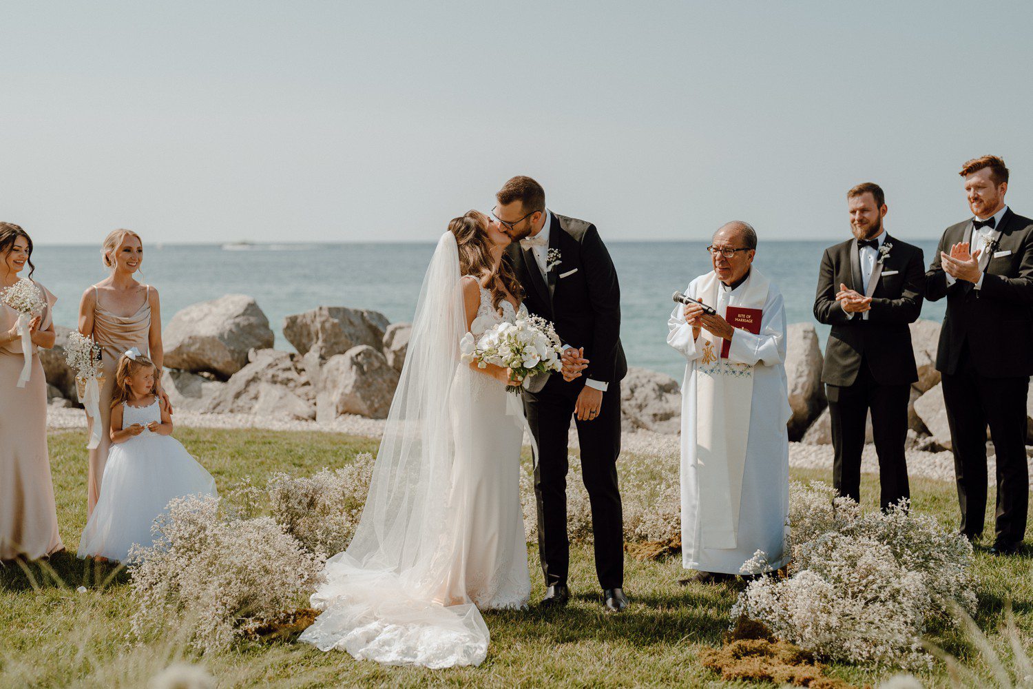 Bride and groom kiss during outdoor wedding at Inn at Bay Harbor on Lake Michigan. 