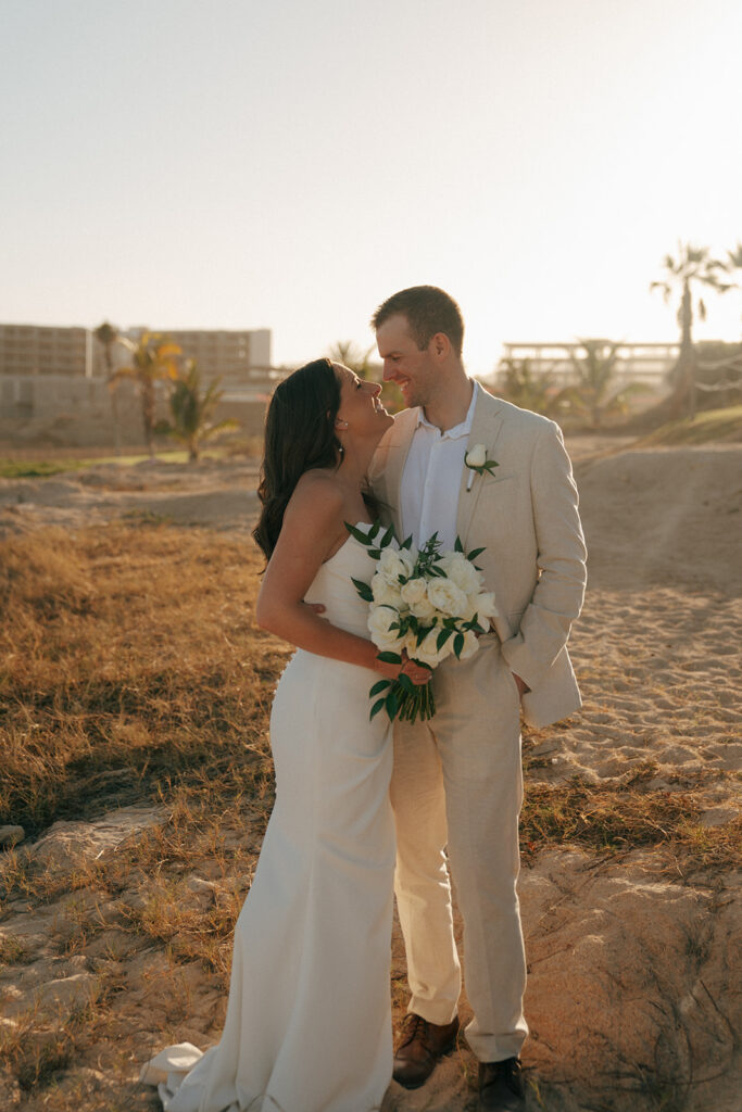 bride and groom looking at each other walking around the beach