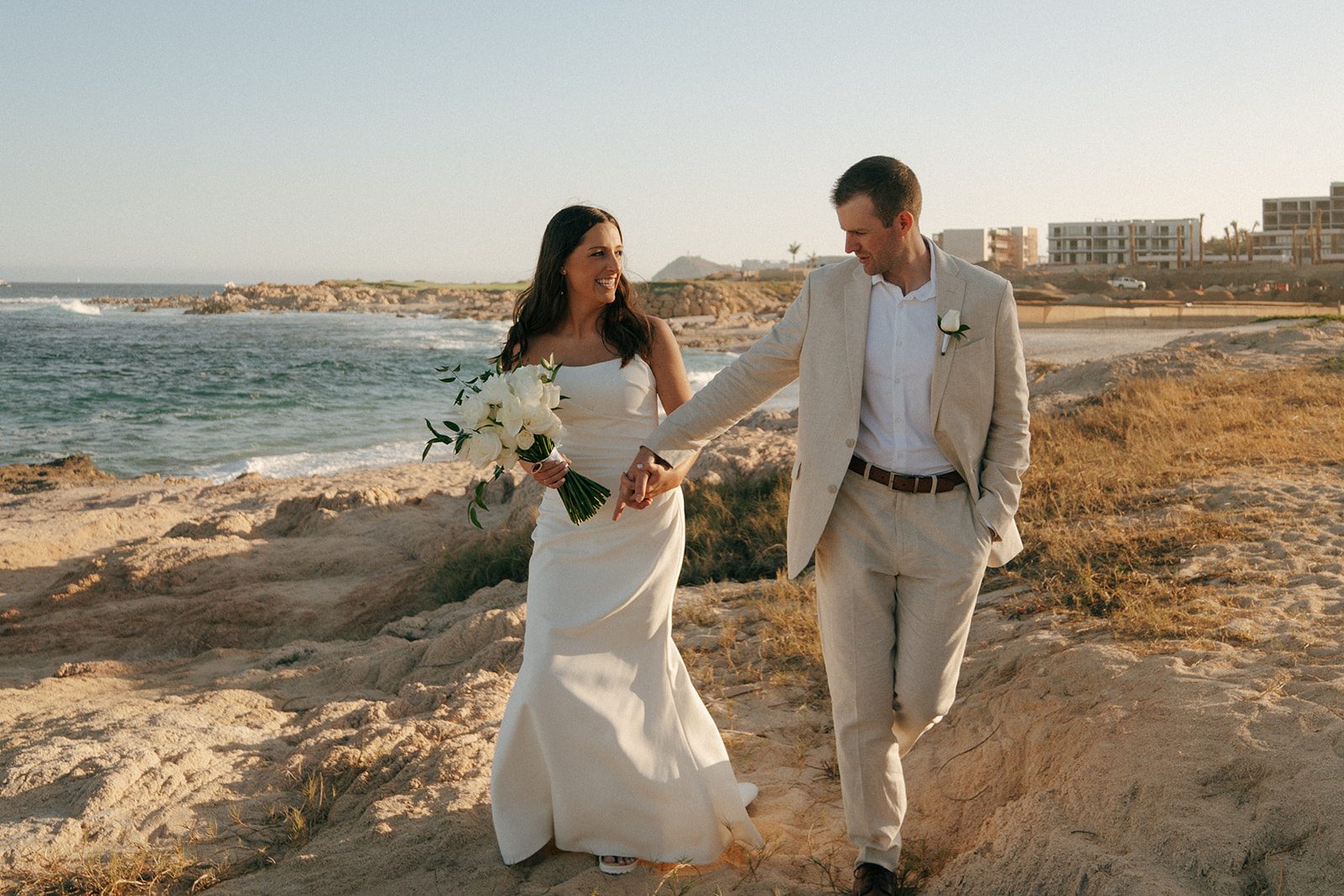 bride and groom holding hands walking around the beach