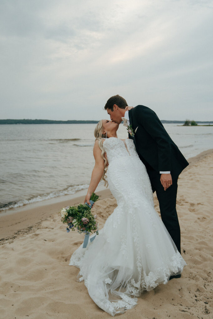 bride and groom kissing at the beach