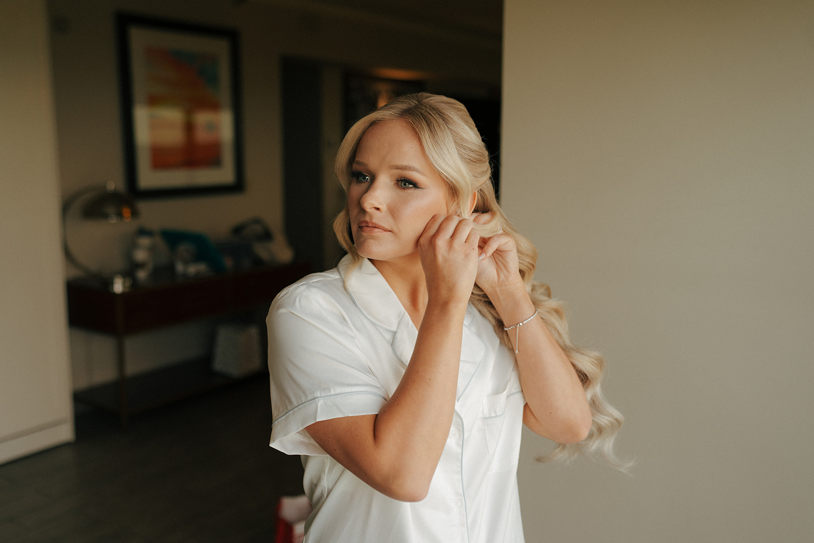 bride putting on her earrings before her wedding ceremony