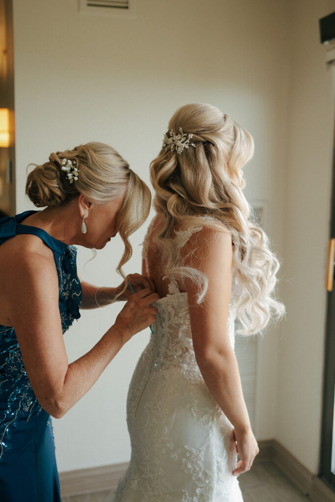 mother of the bride helping her with the wedding dress