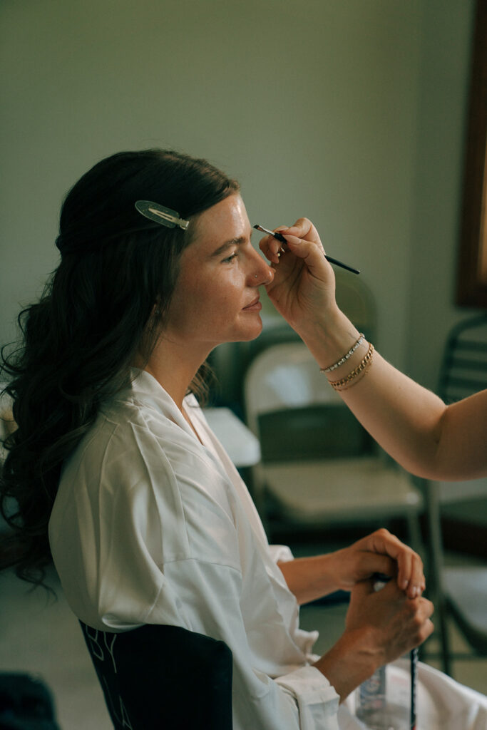 bride getting her makeup done before her wedding ceremony