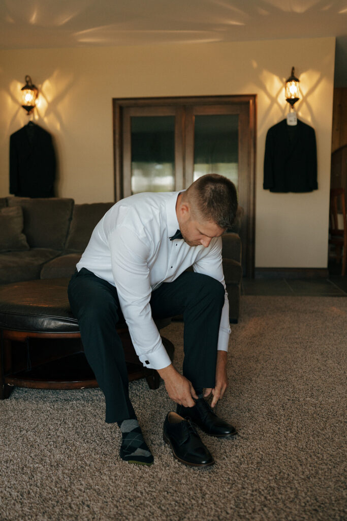 groom putting on his shoes before the wedding ceremony