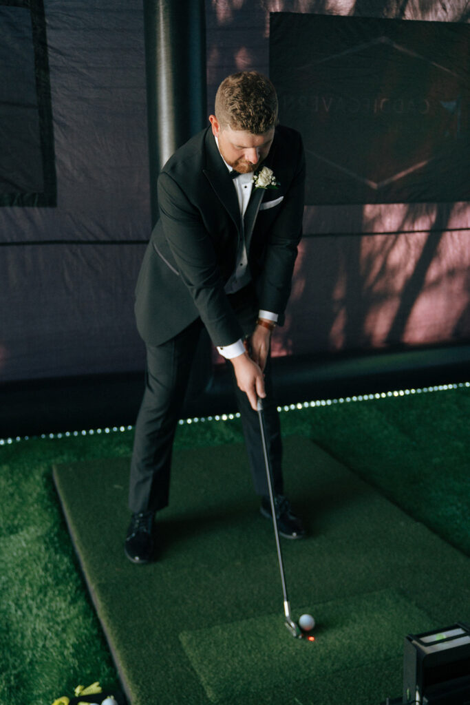 groom playing with his golf simulator