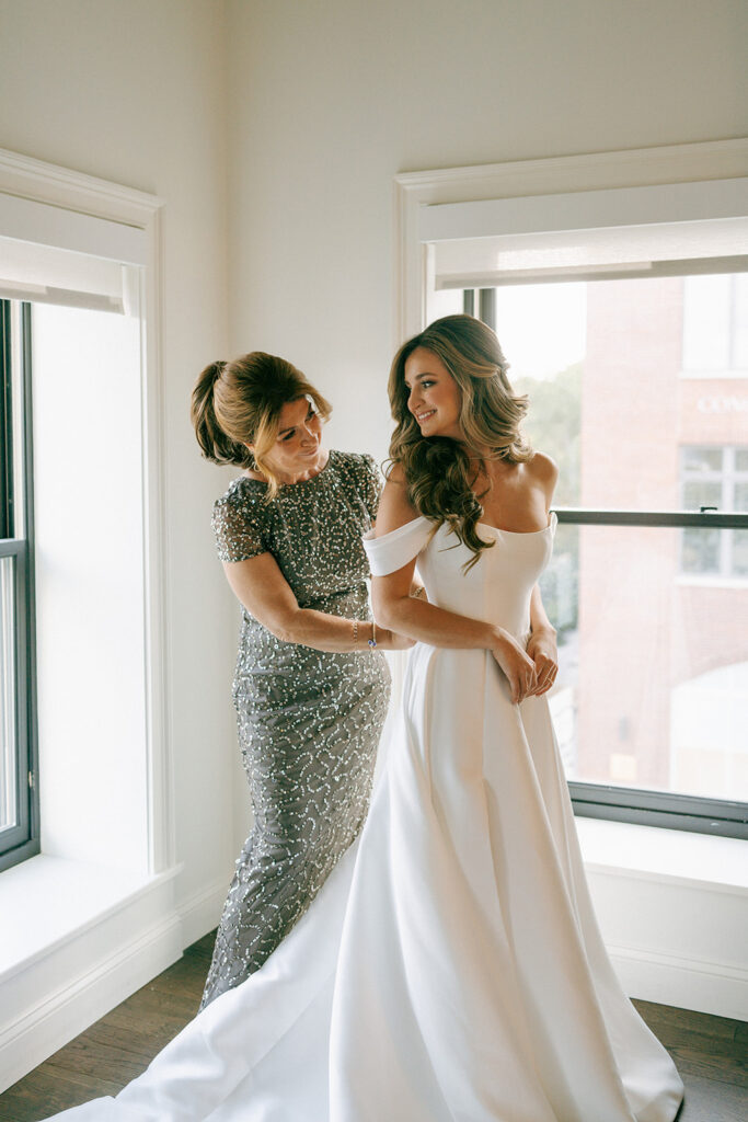 mother of the bride helping helping her with the wedding dress