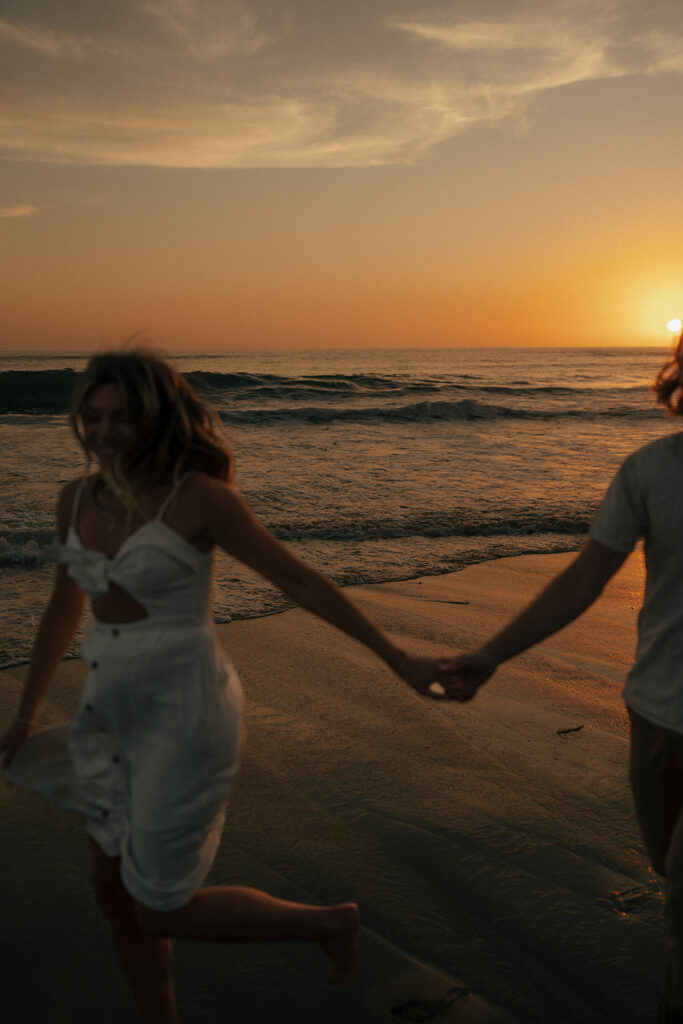 couple holding hands walking around the beach in san diego