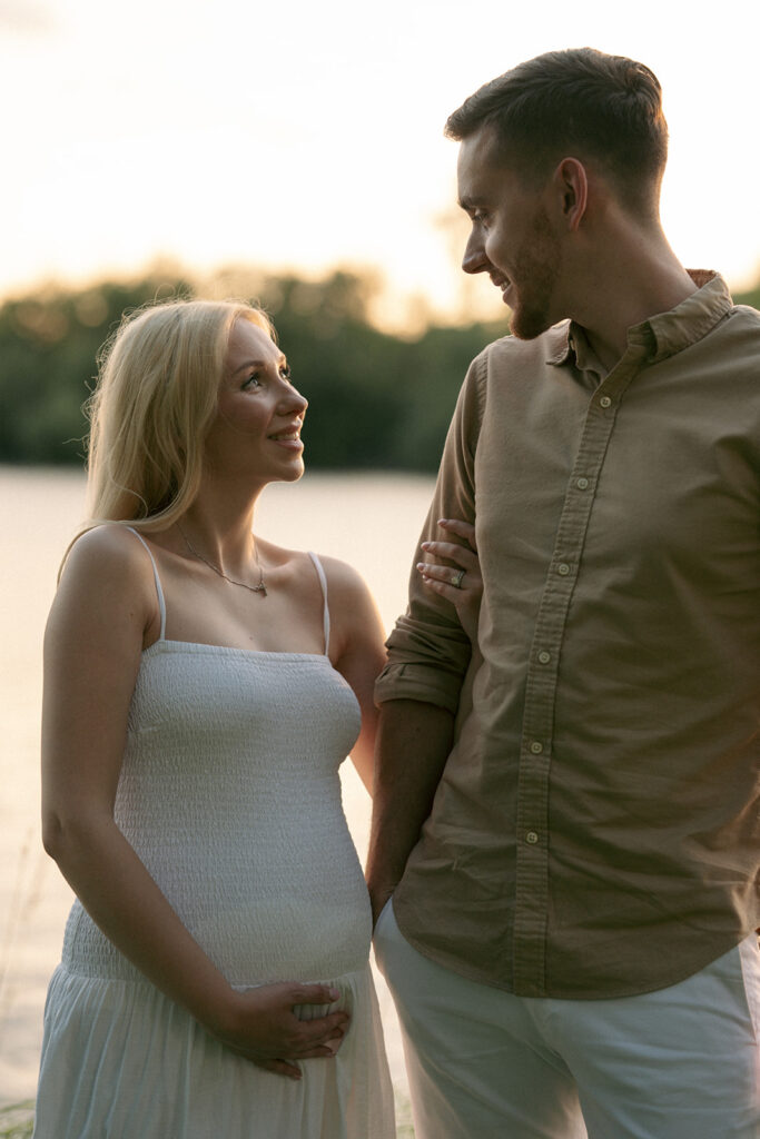 soon to be parents smiling at each other during their session