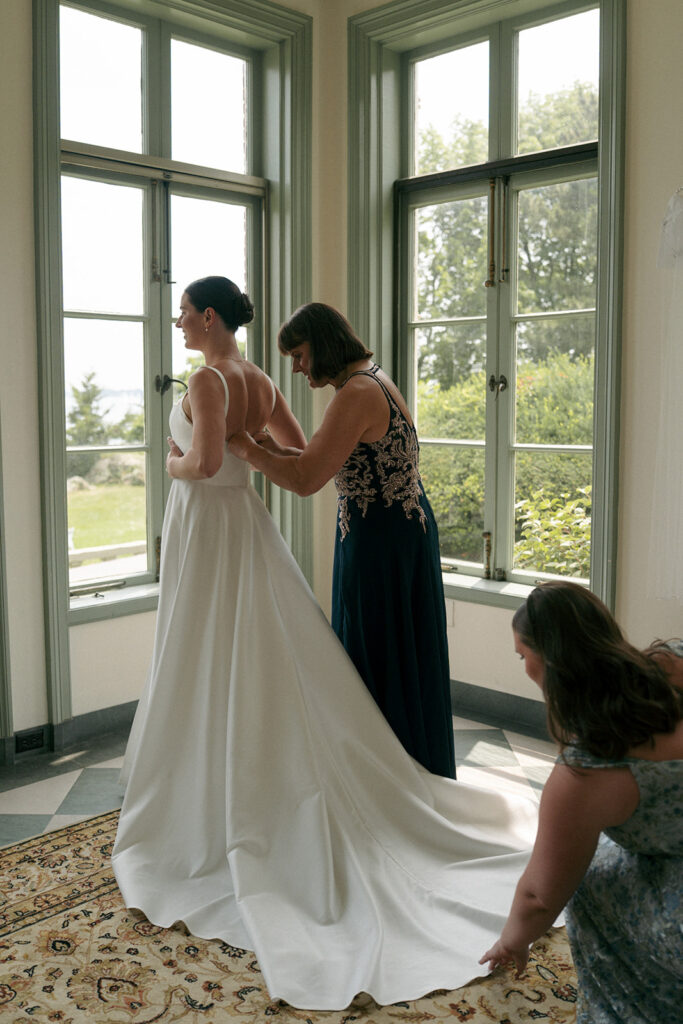 mother of the bride helping her with her wedding dress