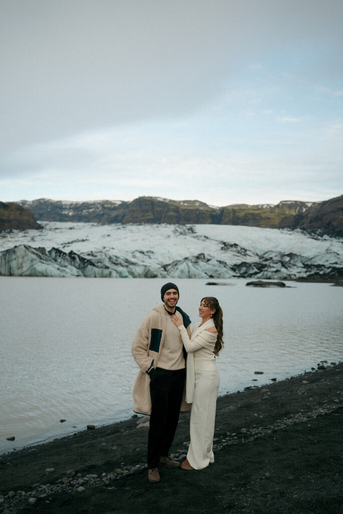 Overhead aerial perspective of couple embracing on white and blue glacier ice in Iceland captured by destination photographer specializing in Iceland engagements