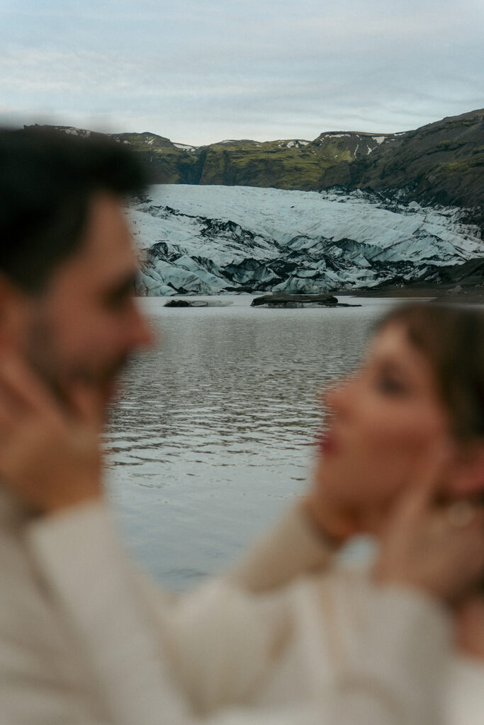 Couple walking away from camera across massive Iceland glacier landscape with stormy skies photographed by Grand Rapids Michigan Iceland engagement photographer