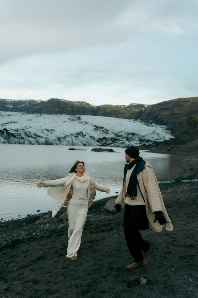 Dramatic black sand and blue ice glacier landscape with engaged couple in Iceland captured by adventure engagement photographer Cassidy Lynne Photo from Michigan