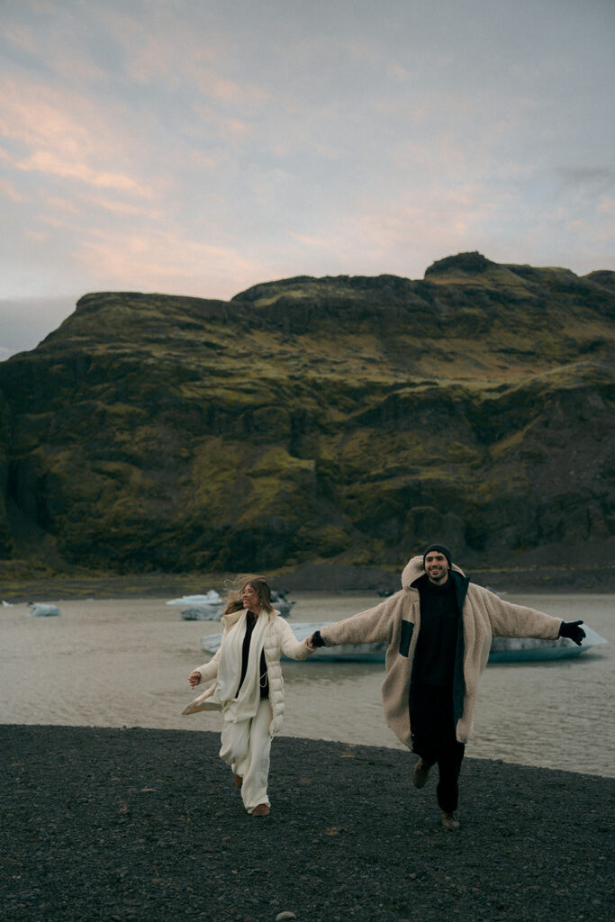 Engaged couple embracing on stunning Iceland glacier during golden hour engagement session photographed by Grand Rapids Michigan Iceland engagement photographer