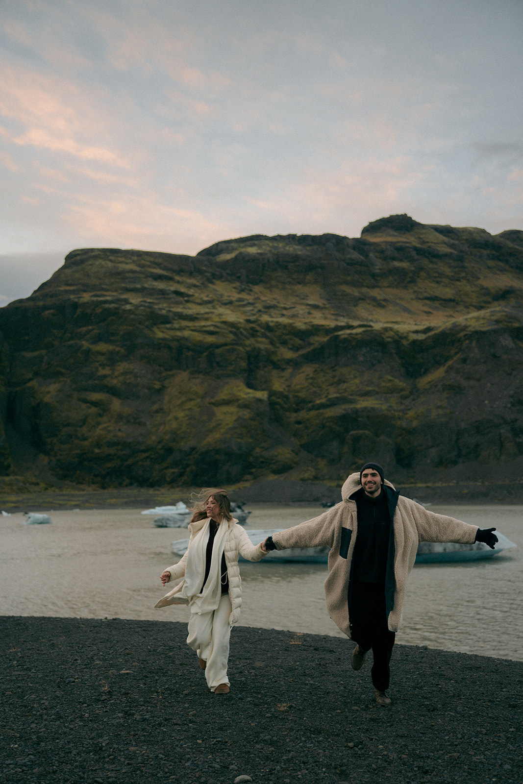 Engaged couple embracing on stunning Iceland glacier during golden hour engagement session photographed by Grand Rapids Michigan Iceland engagement photographer