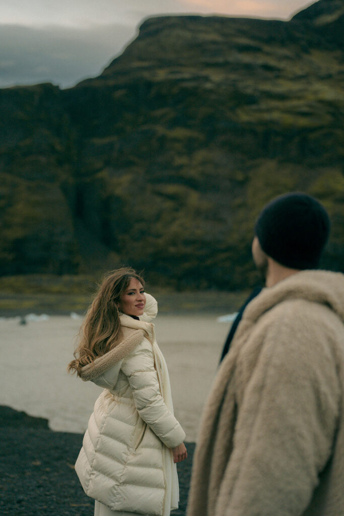 Romantic kiss between engaged couple on dramatic Iceland glacier ice cave with blue tones photographed by Iceland engagement photographer from Michigan