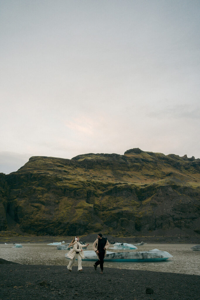 Close up of couple laughing together on Iceland glacier with ice formations behind them captured by destination engagement photographer Cassidy Lynne Photo