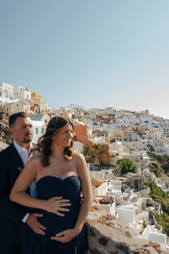 Maternity couple walking through narrow blue door alleyway in Oia Santorini Greece