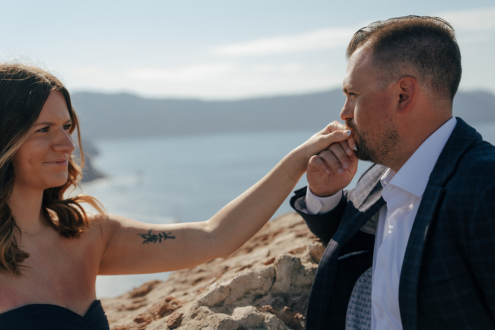 Expectant mother in flowing white dress overlooking Aegean Sea caldera in Santorini Greece