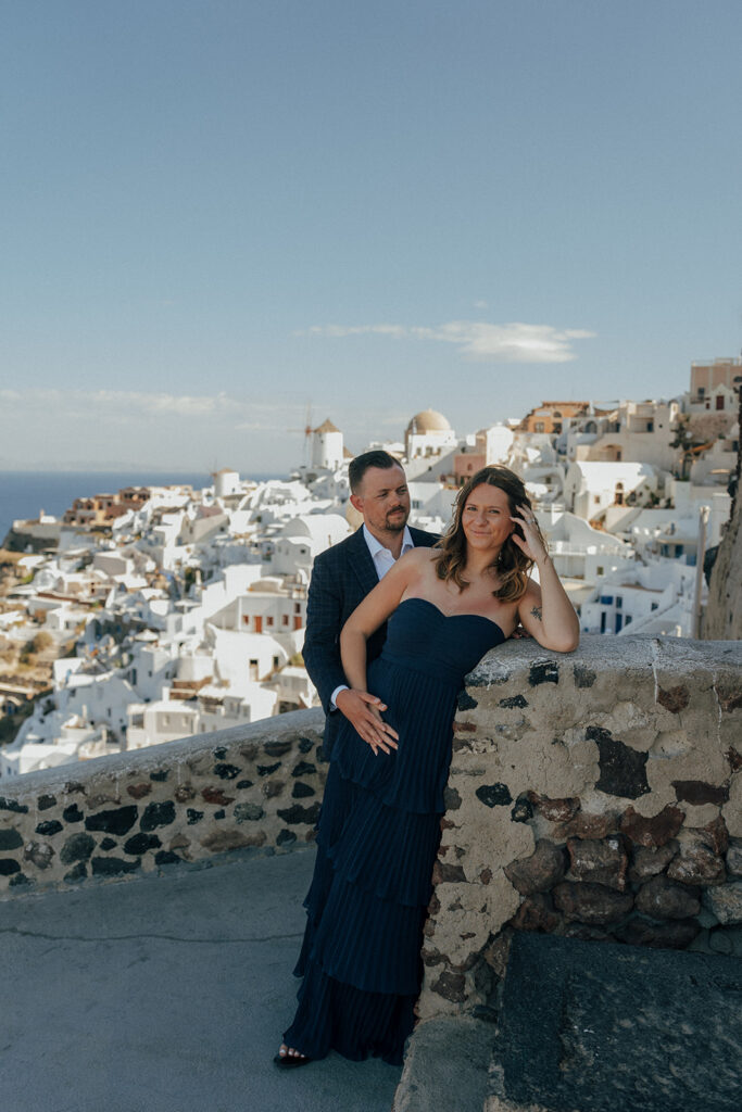 Close up of pregnant belly with husband hands in Oia Santorini Greece white architecture