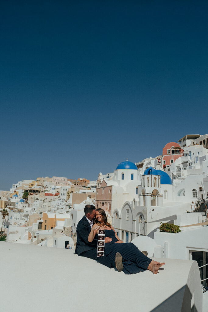 Pregnant woman twirling dress on Santorini rooftop Greece destination couples photoshoot