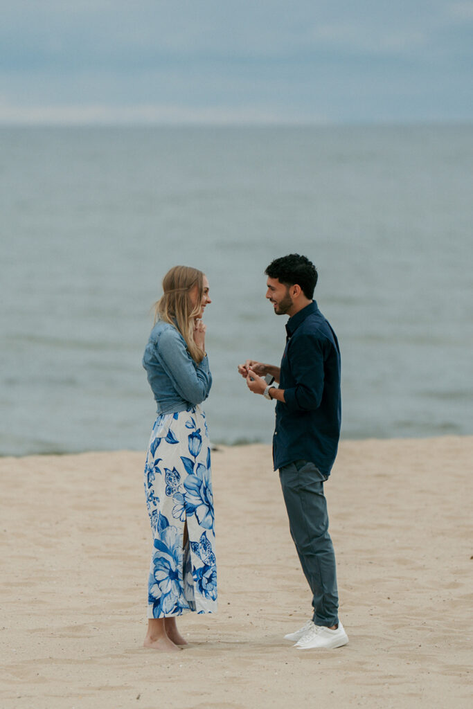 Newly engaged couple kissing on sandy beach at Oval Beach Saugatuck Michigan