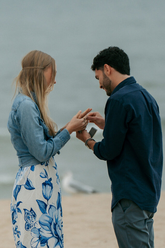 Man proposing on one knee at Oval Beach with Lake Michigan waves in background