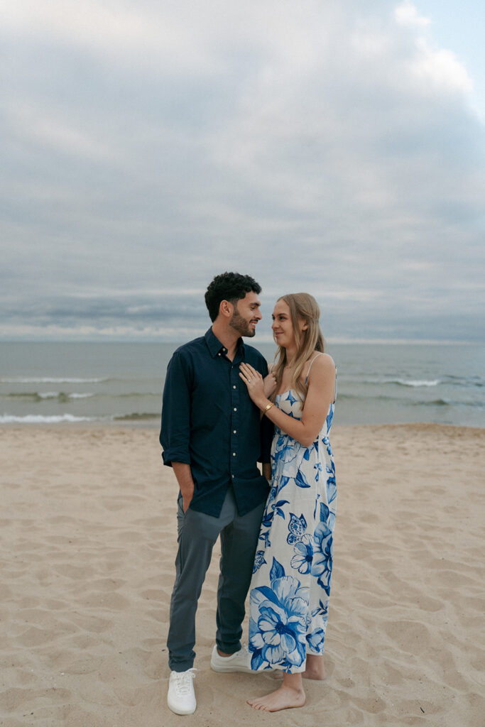 Couple walking hand in hand along Lake Michigan shoreline after proposal
