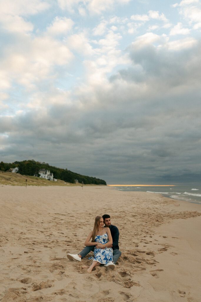 Couple embracing during surprise beach proposal at Oval Beach in Saugatuck Michigan