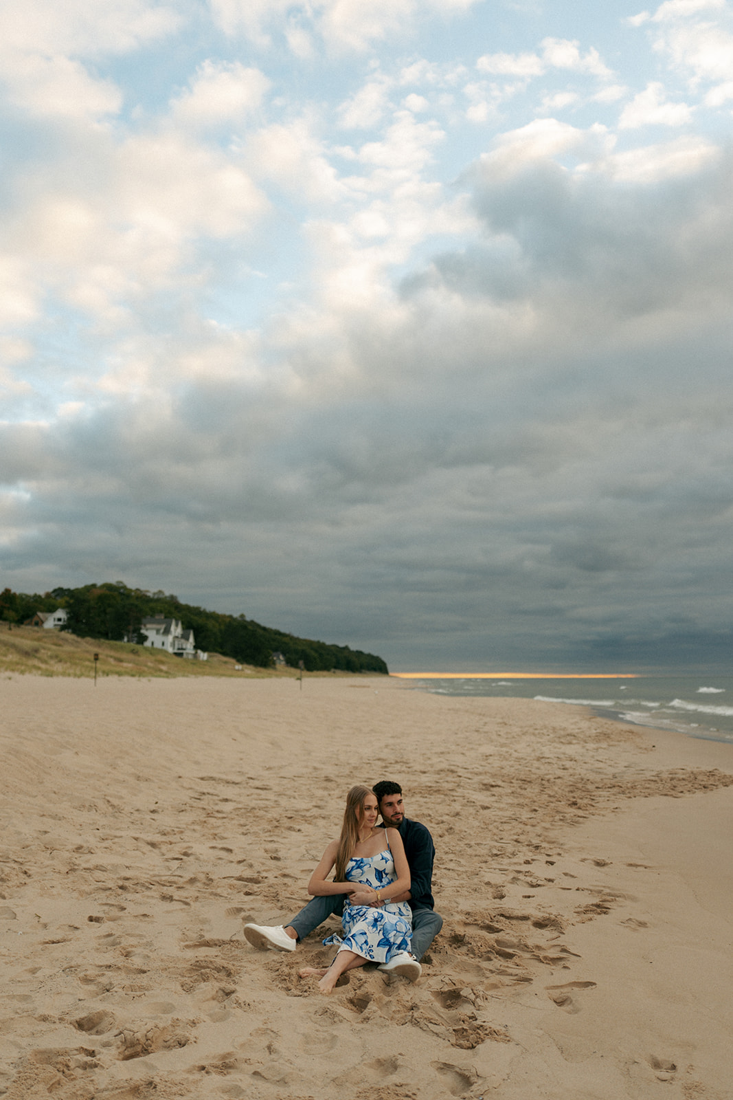 Couple embracing during surprise beach proposal at Oval Beach in Saugatuck Michigan