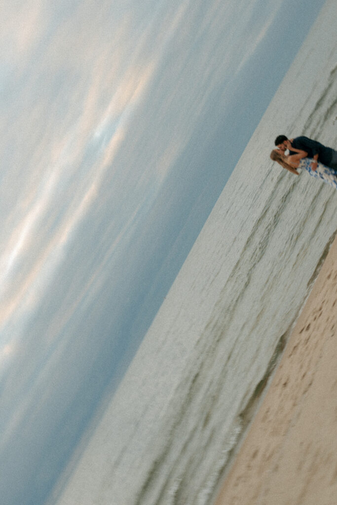 Couple holding hands showing engagement ring at Lake Michigan beach proposal