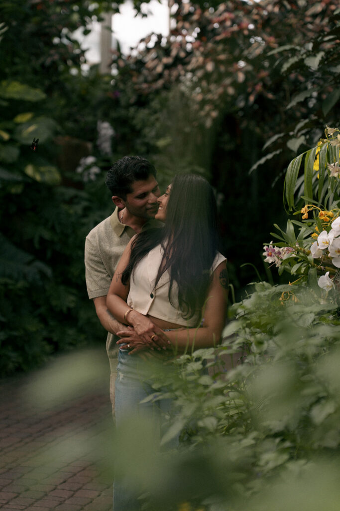 Engaged couple embracing in tropical conservatory at Frederik Meijer Gardens Grand Rapids