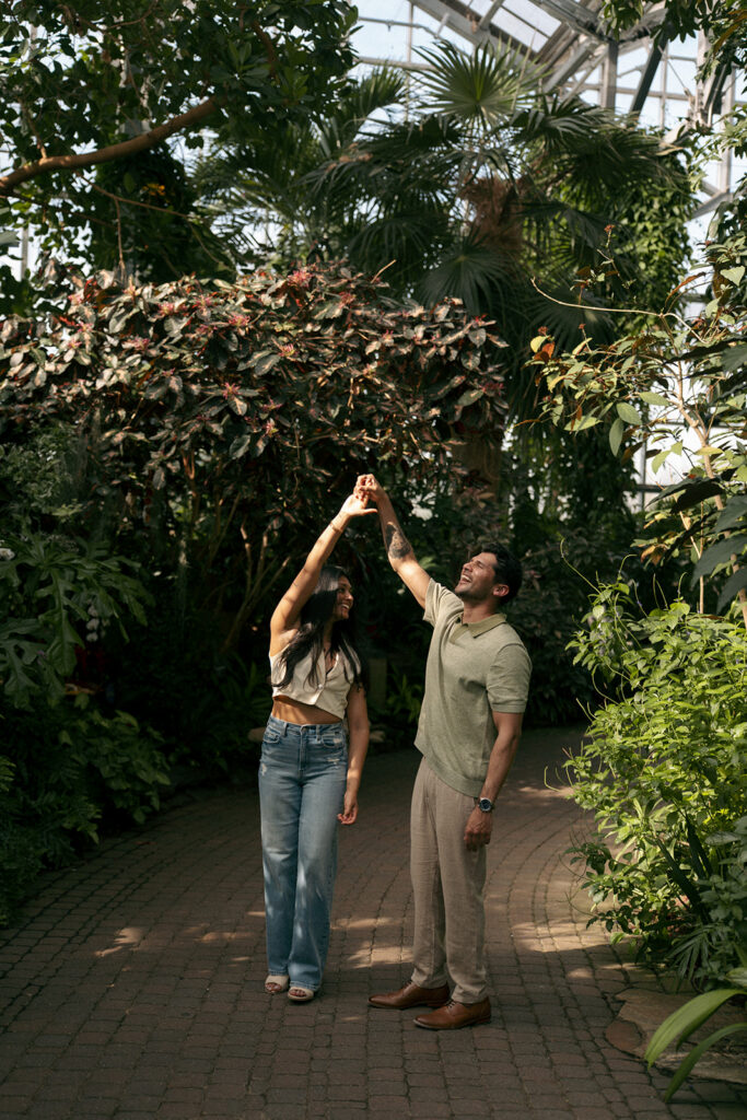 Engaged couple walking hand in hand through garden pathways in Grand Rapids Michigan